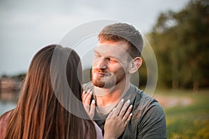 Young couple enjoying the sunset by the lake. Man gazing at his girlfriend