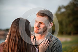 Young couple enjoying the sunset by the lake. Man gazing at his girlfriend