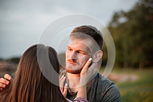 Young couple enjoying the sunset by the lake. Man gazing at his girlfriend