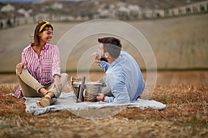 A young couple enjoying wine on the picnic on a large meadow. Relationship, together, love, picnic