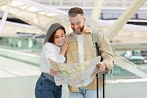 Young Couple Examining Map At Urban Transport Hub Or Airport