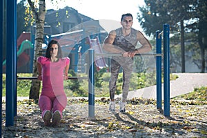 Young Couple Exercising With Dips Bar