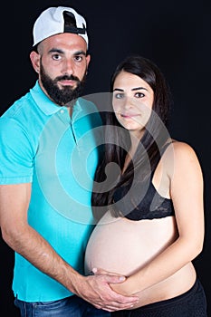 Young couple expecting new baby in black background