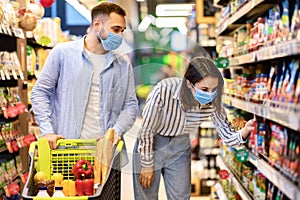 Young couple in face masks shopping in supermarket