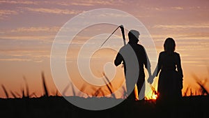 Young couple of farmers in the field, enjoying the sunset. Startup in the agribusiness concept