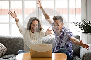 Young couple feeling excited by online win looking at laptop