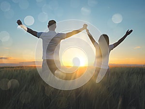 Young couple feeling free in a beautiful natural setting, in what field at sunset