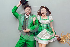 Young couple in festive costumes saint patrick`s day top view looking camera surprised