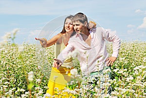 Young couple on field of flowers pointing