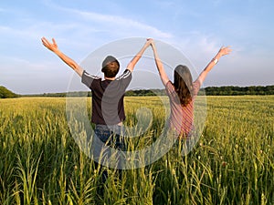 Young Couple in Field Holding Hands Up