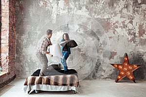 Young couple fighting pillows in the loft style bedroom