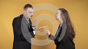 Young couple figuring things out cursing and gesticulating over yellow background.