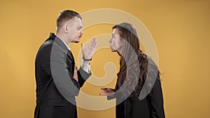 Young couple figuring things out cursing and gesticulating on a yellow background.