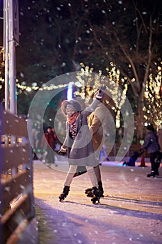 A young couple first time on skates having troubles at ice rink. Skating, closeness, love, together