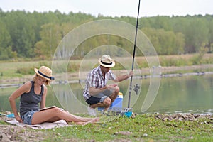 Young couple fishing or angling on lake shore