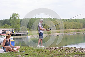 young couple fishing on banks pond