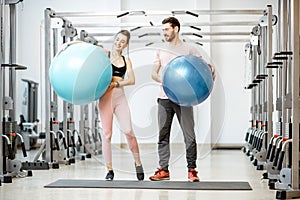 Young couple with fitness ballls at the gym