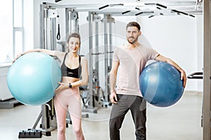 Young couple with fitness ballls at the gym