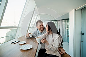 Young couple flirting in coffee shop. Beautiful woman with long dark hair and good looking man with stylish haircut look