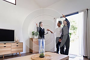 Young couple follow a real estate agent who is giving them a tour around a home, showing all the room and telling about