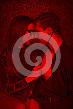 Young couple foreplay with whip in red light photo