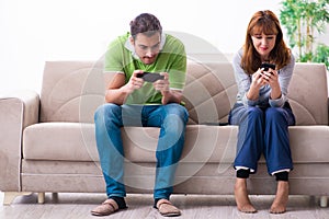 Young couple in gadget dependency concept