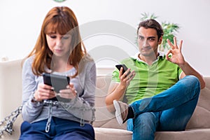 Young couple in gadget dependency concept