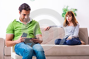 Young couple in gadget dependency concept