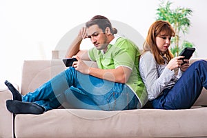 Young couple in gadget dependency concept