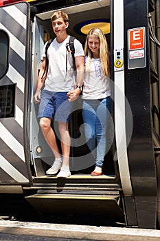 Young Couple Getting Off Train At Platform