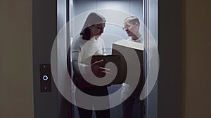 Young couple getting out of the elevator with cardboard boxes moving in to new appartment