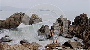 Young couple girl and man are standing on the beach and holding each other`s hands. Beautiful view of the ocean and