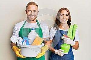 Young couple of girlfriend and boyfriend wearing apron holding products and cleaning spray smiling with a happy and cool smile on