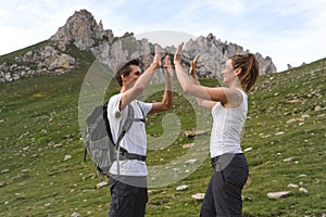 Young couple giving high five on the top of the mountain. Swiss alps