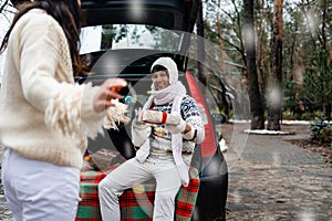 Young couple giving presents and looking each other sitting in the trunk in winter holidays.