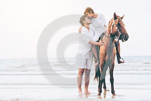 Young couple goes horse riding on tropical beach.