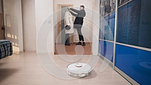 A young couple goes for a walk while the robot vacuum cleaner is cleaning.