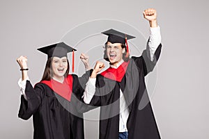 Young Couple in graduation gowns holding diplomas and celebrate isolated on white background