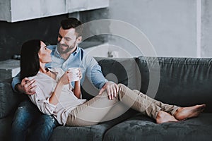 Young Couple on Gray Sofa with Pillows at Home.
