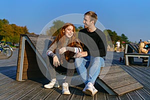 young couple are sitting in the park on a wooden bench hugging