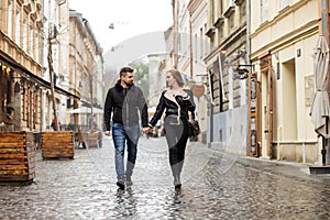 Young couple guy and girl walking through the beautiful spring and autumn streets of a European city, the concept of love