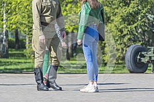 Young couple, guy in military uniform and girl in civilian clothes, stand on street and say goodbye. Mass mobilization.