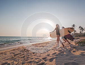 Young couple of happy smiling surfers run with surfboards on ocean coast, sport active lifestyle