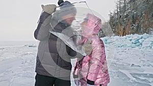 Young couple has fun during winter walk against background of ice of frozen lake. Love story. Lovers keep an ice floe