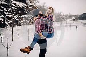 Young couple has fun during winter walk on ice of frozen lake.