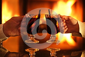 Young couple has romantic dinner with mulled wine over fireplace background.