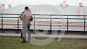 Young couple have fun, laugh standing on a roof. A beautiful view of brunette lovers. Happy love relationship.