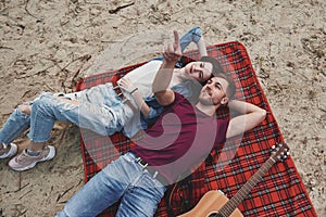 Young couple have picnic on the beach. Lying on the red colored blanket