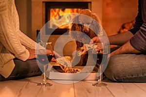Young couple have romantic dinner with pizza and wine over fireplace background.