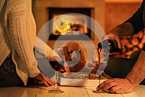 Young couple have romantic dinner with pizza and wine over fireplace background.